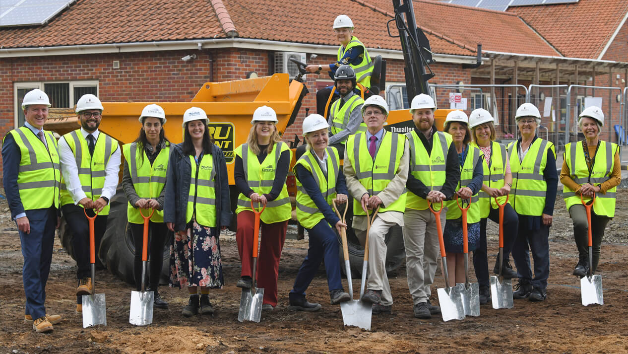 Group of People in PPE standing on building site with shovels